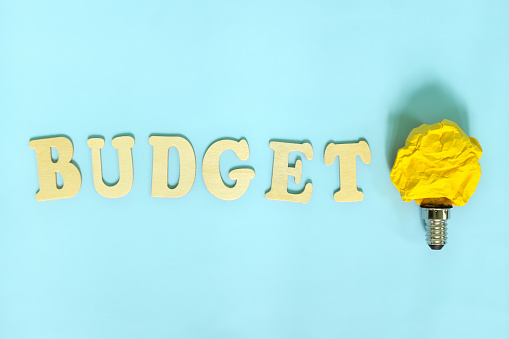 How to budget and budgeting ideas and tips concept. Bright yellow crumpled paper light bulb.