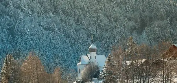The Kapelle St. Nikolaus before a tree-covered slope on a winter day in Fussen