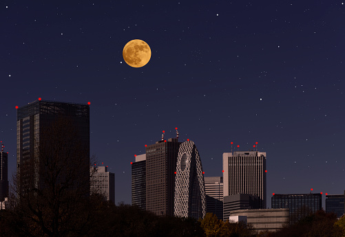 Full strawberry moon rising over the Tokyo Shinjuku skyline with copy space.