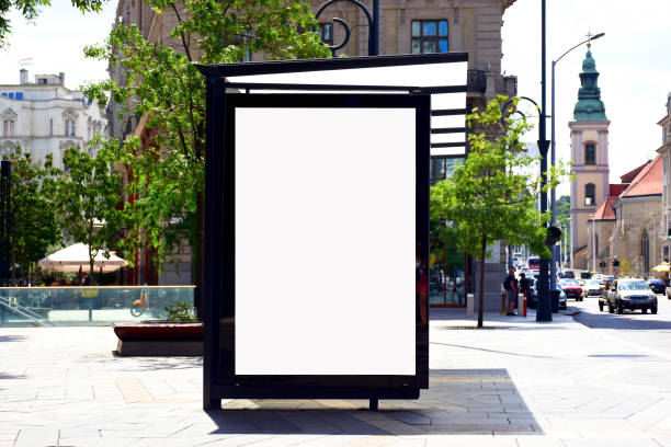 bus stop with blank white lightbox ad billboard sign. background for mock-up. composite image empty white exterior poster ad and billboard display glass lightbox panel. aluminum frame structure. street perspective with European streetscape and trees. urban street setting bus shelter stock pictures, royalty-free photos & images