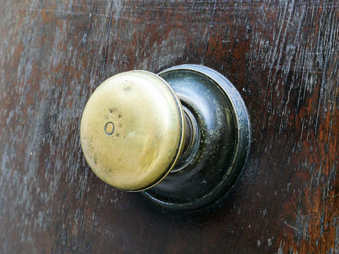 Perugia, Italy, 2022. A worn round door knob on a wooden surface.