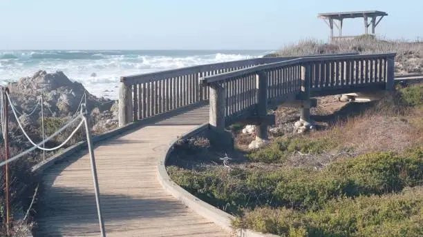 Photo of California ocean coast. 17-mile drive wooden boardwalk trail, Pebble beach waves