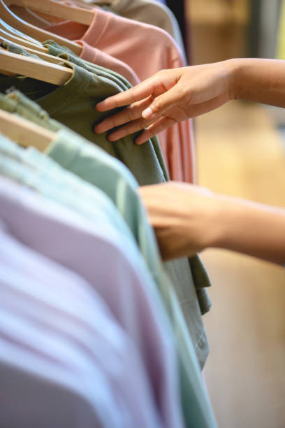 donna che sceglie i vestiti prima dello shopping - negoziante di tessuti foto e immagini stock