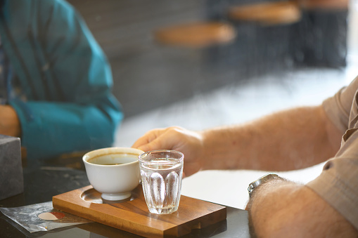 Two friends in a cafe, the usual morning coffee with a glass of cold water and talking about casual topics