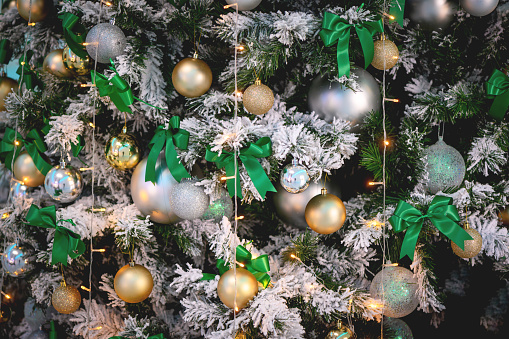 Christmas tree with white branches decorated with gold and silver balls and decorative lights, close-up