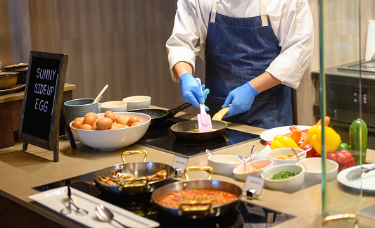 Unrecognizable chef preparing scrambled eggs for breakfast