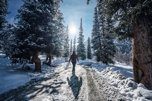 Rear view of the woman walking by the road in the mountains