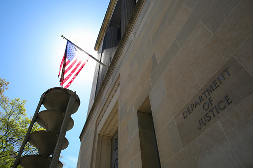 US Department of Justice building and the American flag under the sun, Washington DC, United States