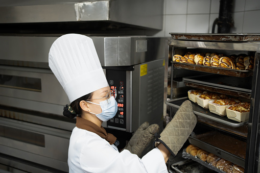 Female baker is arranging bread