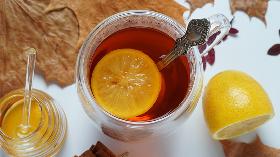 Autumn hot tea with cinnamon sticks and lemon in transparent cup