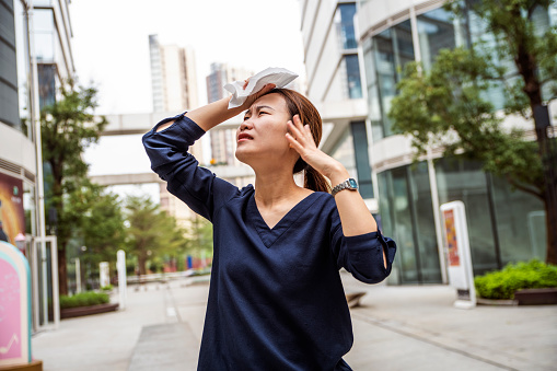 Young female suffering city heat, waving napkin, trying to cool down