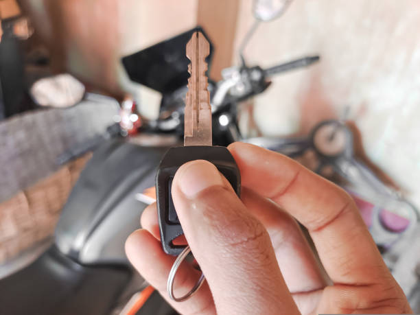 homem segurando uma chave com fundo de motocicleta. compra de motocicletas, passeios de bicicleta ou conceito de viagem de fim de semana - motorcycle handlebar road riding - fotografias e filmes do acervo