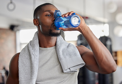 Drinking water, yoga and black man with a bottle after workout and wellness exercise. Relax, zen and drink for wellbeing in a home living room for meditation, pilates or zen practice at a house