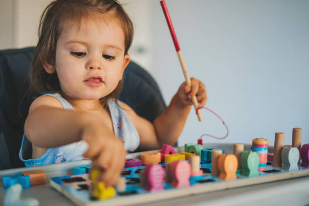 istock Playful cute little baby girl learning numbers and math with blocks for educational development at home. Education concept. School education. People lifestyle concept. 1449298366