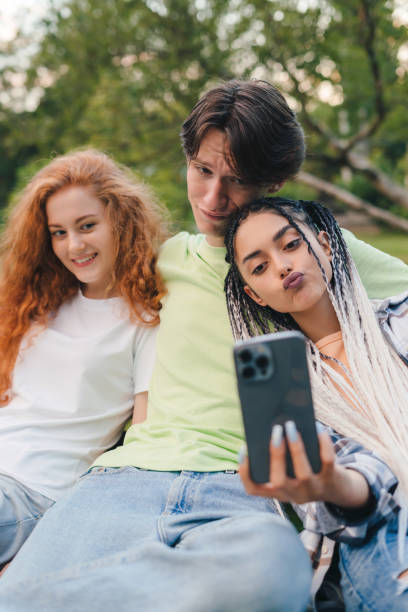 istock Three friends taking a selfie outdoors on sunny summer day, sitting in the bark. Summer vacation fun. Having fun. 1449298418
