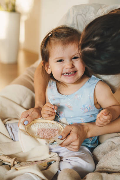 istock Mother and daughter spending time together at home, doing handicrafts with needle and thread. Family education. Family concept. Attractive beautiful girl. Happy family. Love people concept. 1449300173