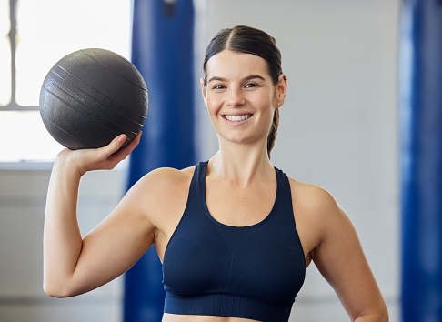 Sports, training and woman with a medicine ball for exercise, fitness and body goal at gym. Portrait of happy, healthy and athlete with a smile for workout for wellness at club for health and cardio