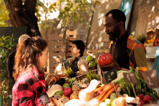 istock Man vendor standing behind stall selling fresh organic vegetables 1449304880