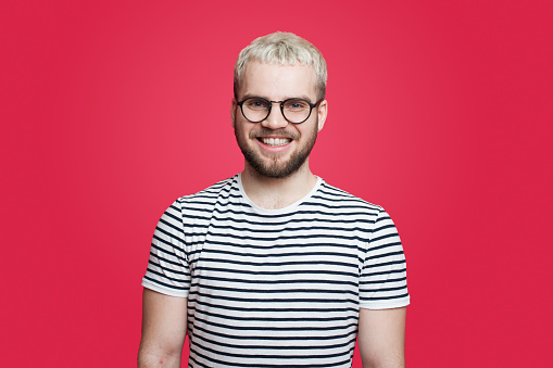 Close up portrait of happy smiling bearded hipster man with eyeglasses and looking confident at the camera isolated over red background. Happy people positive emotion. Positive person.