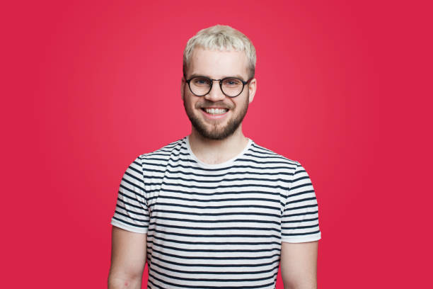 Close up portrait of happy smiling bearded hipster man with eyeglasses and looking confident at the camera isolated over red background. Happy people positive emotion. Positive person. stock photo