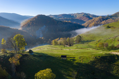 Mountain countryside homestead in the autumn. Wooden barns, aerial drone view. Transylvania, Romania