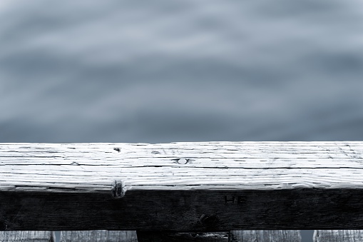 A part of a wooden dock with the blurred background of the lake