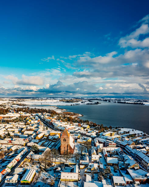 Drone’s eye view of the medieval town of Stege on the island of Moen in Denmark, covered in snow, photographed late November 2022. Colour, vertical format with lots of copy space. Stege’s history can be traced back to medieval times when it was an important part of the herring trade and a staging post for the Hanseatic League