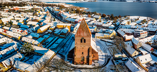 Drone’s eye view of the medieval town of Stege on the island of Moen in Denmark, covered in snow, photographed late November 2022. Colour, horizontal format with some copy space. Stege’s history can be traced back to medieval times when it was an important part of the herring trade and a staging post for the Hanseatic League
