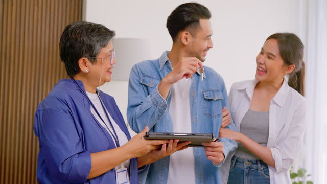 Young family purchasing house getting keys from Real Estate Agent with happiness emotion indoors.
