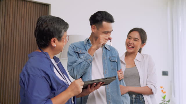 Proud to be owner . Crop shot of young happy family purchasing new house getting keys from Real Estate Agent indoors. Housing and real estate business concept.