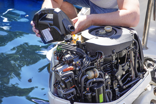 A Man pouring and refueling engine motor oil into the engine for boat or yacht.