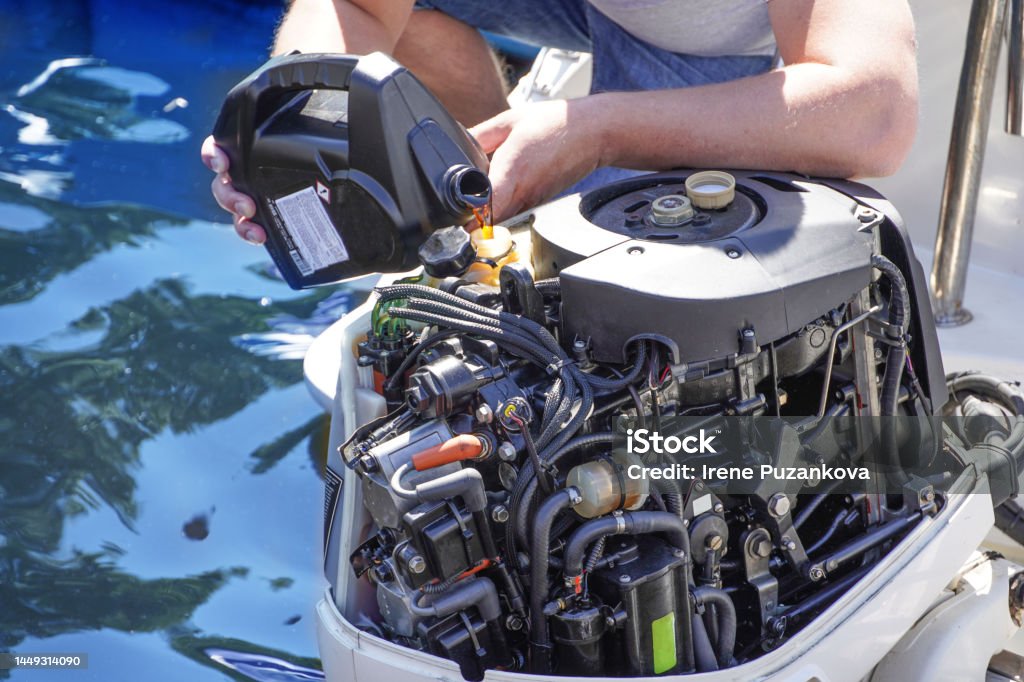 A Man pouring and refueling engine motor oil into the engine for boat or yacht. Nautical Vessel Stock Photo