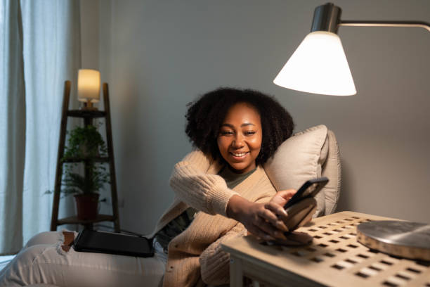Woman putting her smartphone on wireless charger Young woman using mobile phone being placed on a modern wireless power bank. turning on lamp stock pictures, royalty-free photos & images