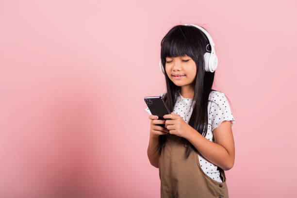 azjatyckie dziecko 10 lat ciesząc się słuchaniem muzyki z telefonu komórkowego nosić bezprzewodowy zestaw słuchawkowy zamknięte oczy - 8 9 years audio zdjęcia i obrazy z banku zdjęć