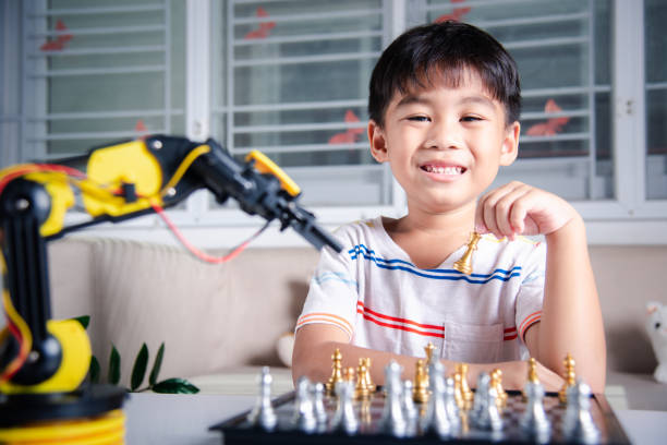 istock Asian little boy is playing chess with robot machine arm 1449315735