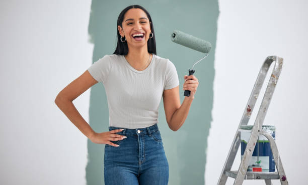 家のリフォーム、部屋のデザインカラー、プロジェクト開発の壁に興奮したポートレートを持つ女性の絵画、はしご、ハードウェア。環境にやさしい緑の絵の具、ブラシ、興奮した、または� - female house painter home decorator paintbrush ストックフォトと画像