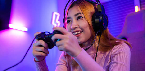 istock Gamer using joystick controller plays online video game with computer neon lights she winning 1449317162