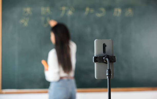 istock Asian teacher teach on board while have blackboard lecture online through smartphone in classroom 1449317236