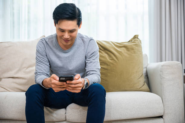 istock middle aged man relaxing sitting on sofa using smart mobile phone at home 1449317291