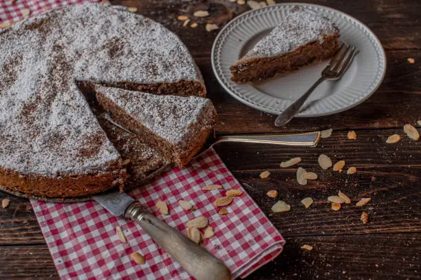 Traditional italian torta caprese, Chocolate, almond cake. Baked with real dark and grated chocolate and almond flour. Served ready to eat on rustic and wooden table background with cross section view