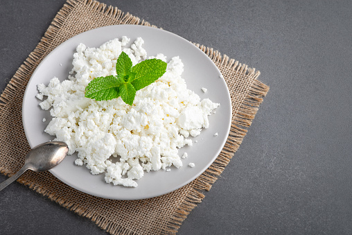 Bowl with fresh cottage cheese on table. Space for text.