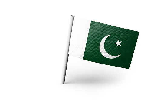 Small paper flag of Pakistan pinned. Isolated on white background. Horizontal orientation. Close up photography. Copy space.
