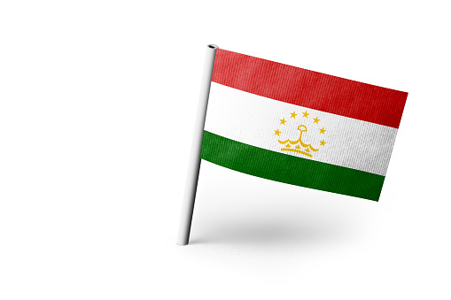 Small paper flag of Tajikistan pinned. Isolated on white background. Horizontal orientation. Close up photography. Copy space.