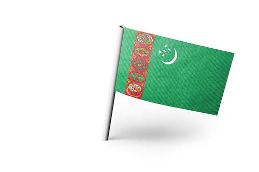 Small paper flag of Turkmenistan pinned. Isolated on white background. Horizontal orientation. Close up photography. Copy space.