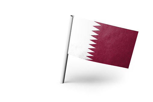 Small paper flag of Qatar pinned. Isolated on white background. Horizontal orientation. Close up photography. Copy space.