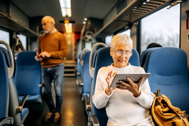 istock Beautiful senior woman using digital tablet while riding in a train 1449320855