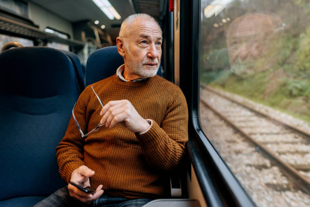 Senior man enjoying a view while riding in a train stock photo