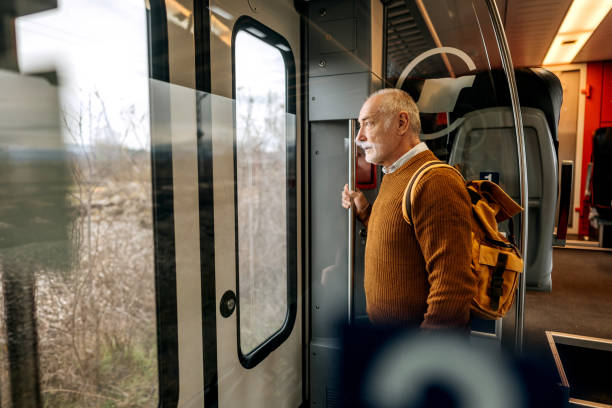 istock Senior man riding in a train next to the train door 1449322058