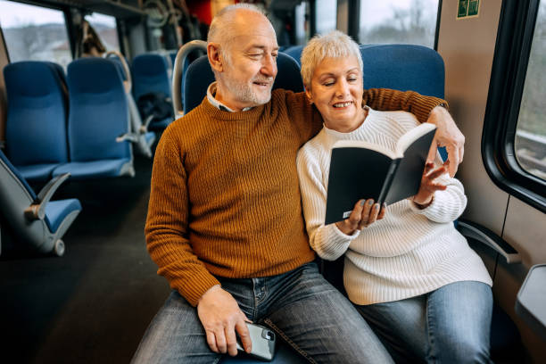 istock Senior couple reading a book together while riding in a train 1449322742
