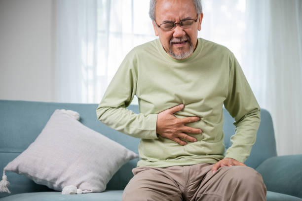 istock Elderly Asian old man sitting on sofa having stomachache 1449325082